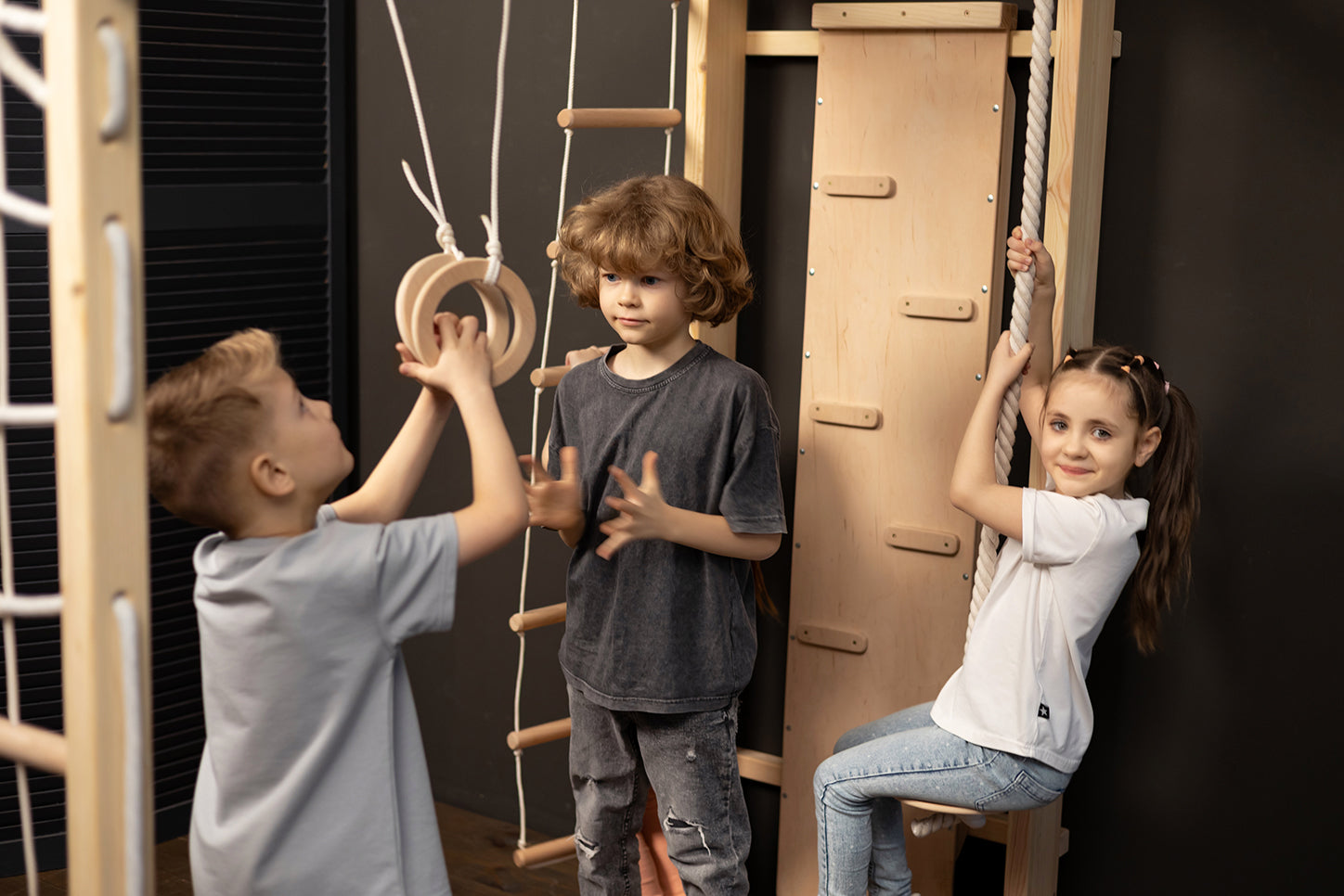 Drei Kinder spielen gemeinsam an der BeLissi Nelo Montessori-Kletterwand